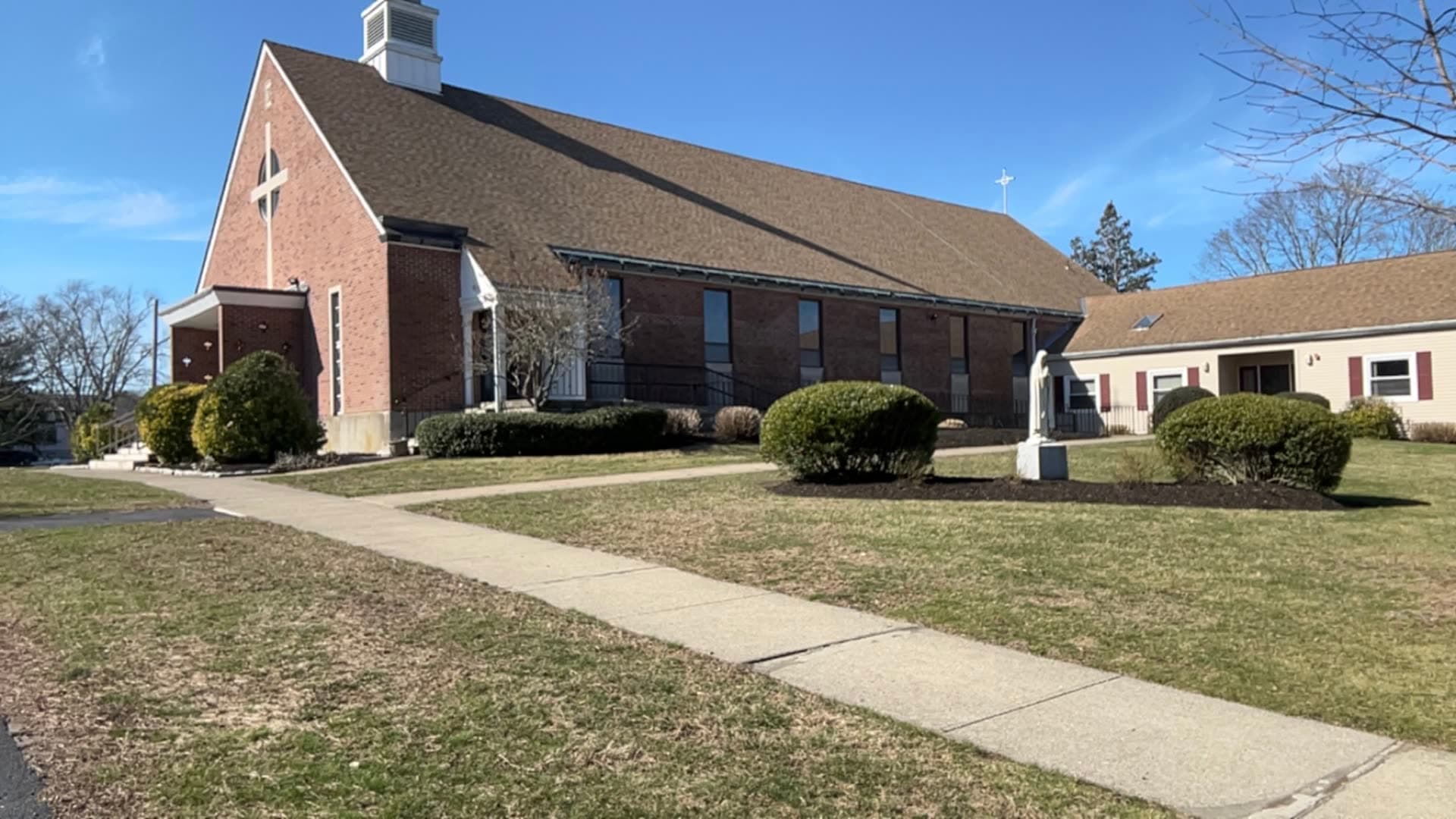 A brick church in the East Bay with trimmed shrubs, mulched beds, and maintained grounds, a LawnCheck commercial property