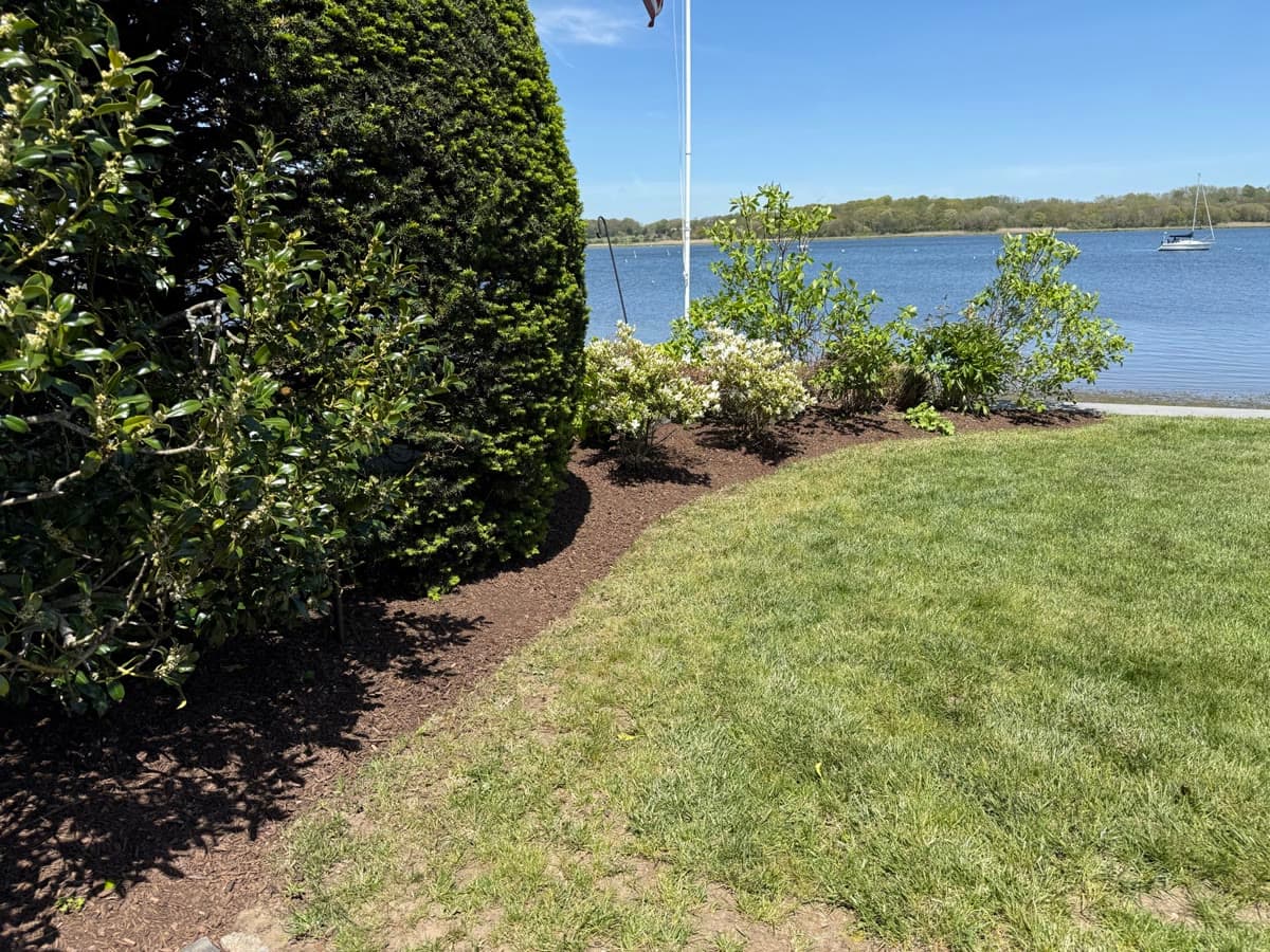 Freshly mulched planting beds and a manicured lawn along a waterfront property