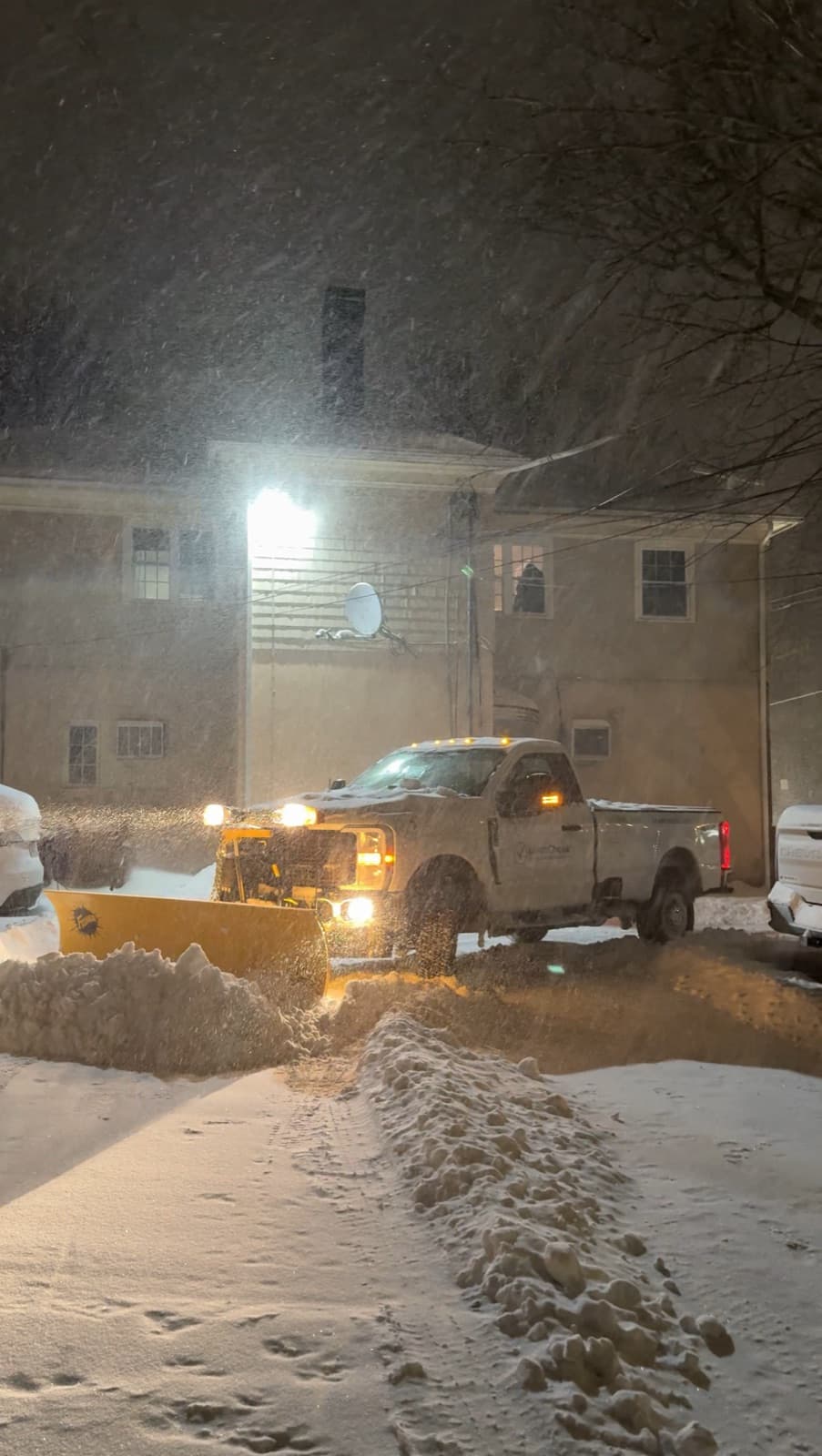 The LawnCheck plow truck clearing a home's driveway during an overnight storm