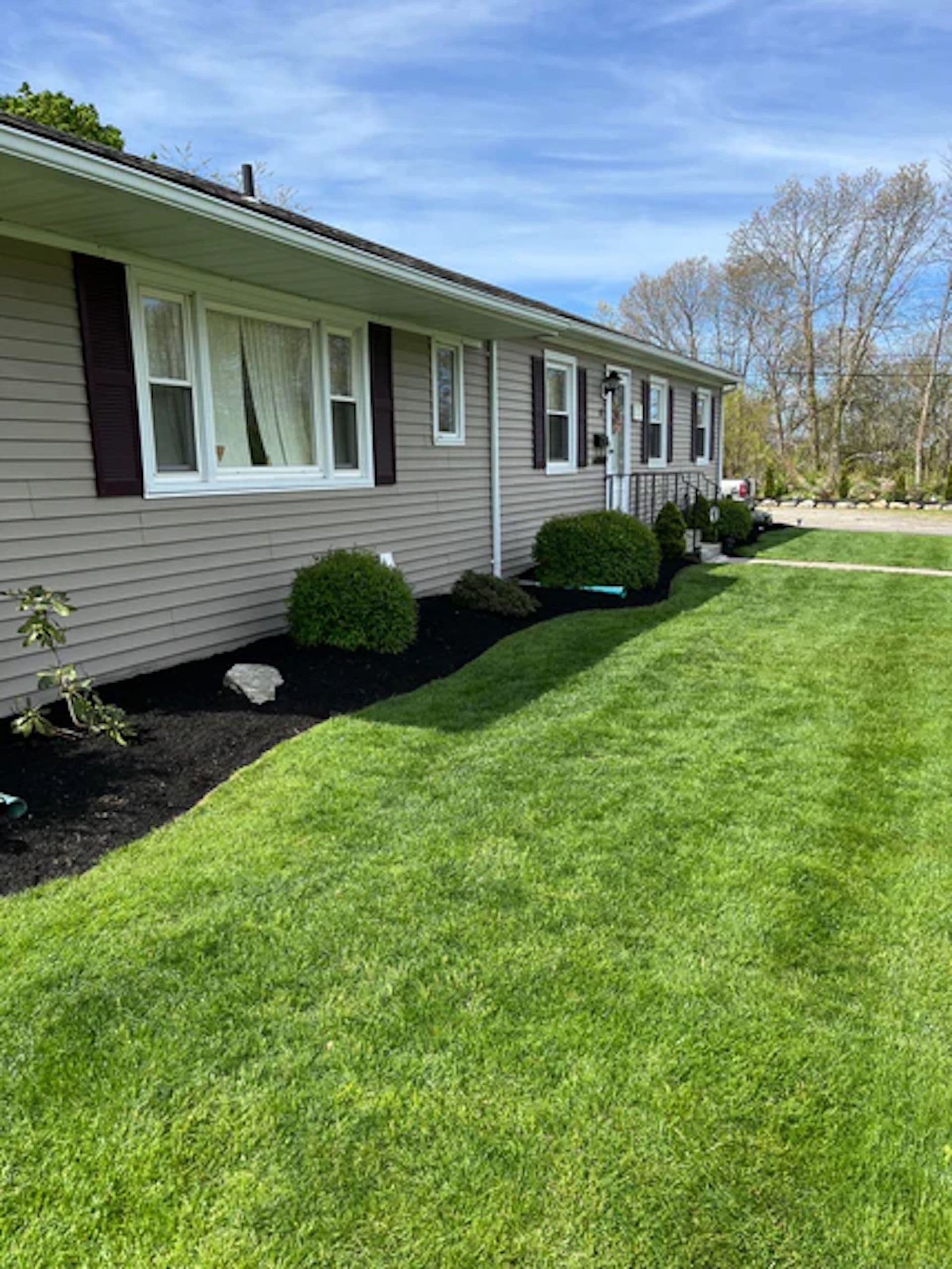 A LawnCheck-maintained home with fresh mulch beds and a healthy green lawn in the East Bay, Rhode Island
