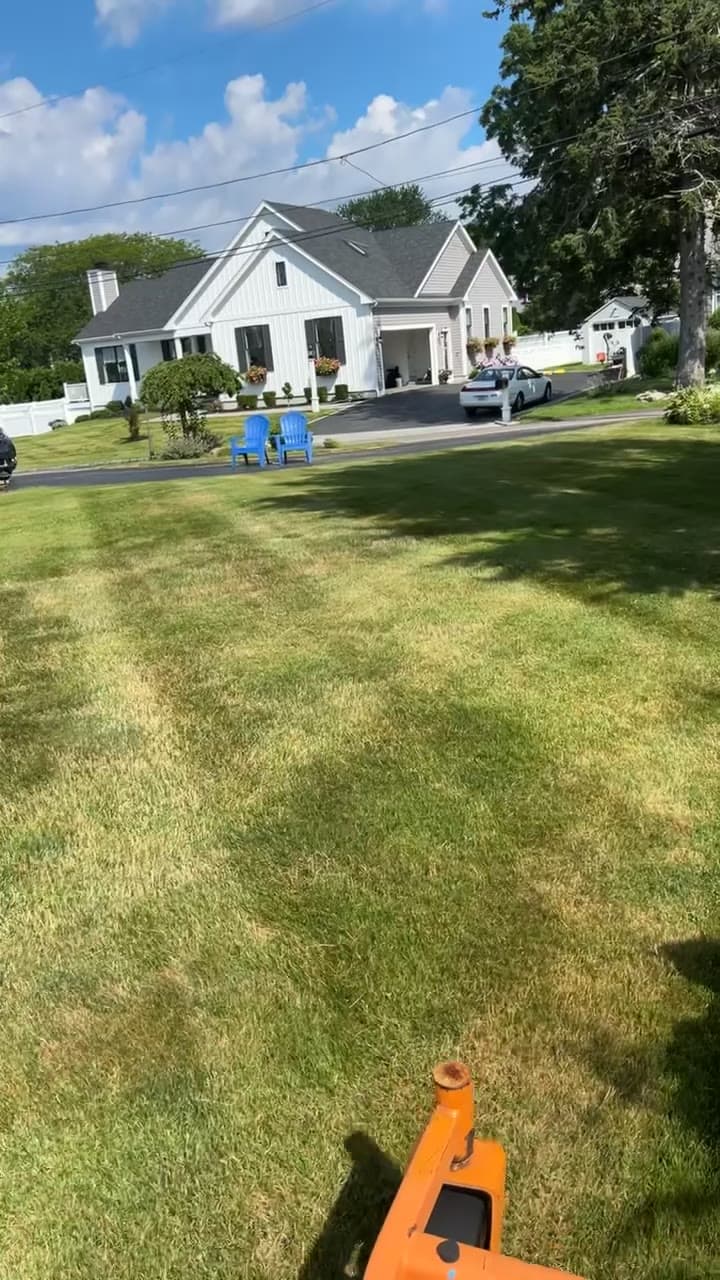 A LawnCheck crew mowing a sunny, freshly striped lawn at an East Bay home