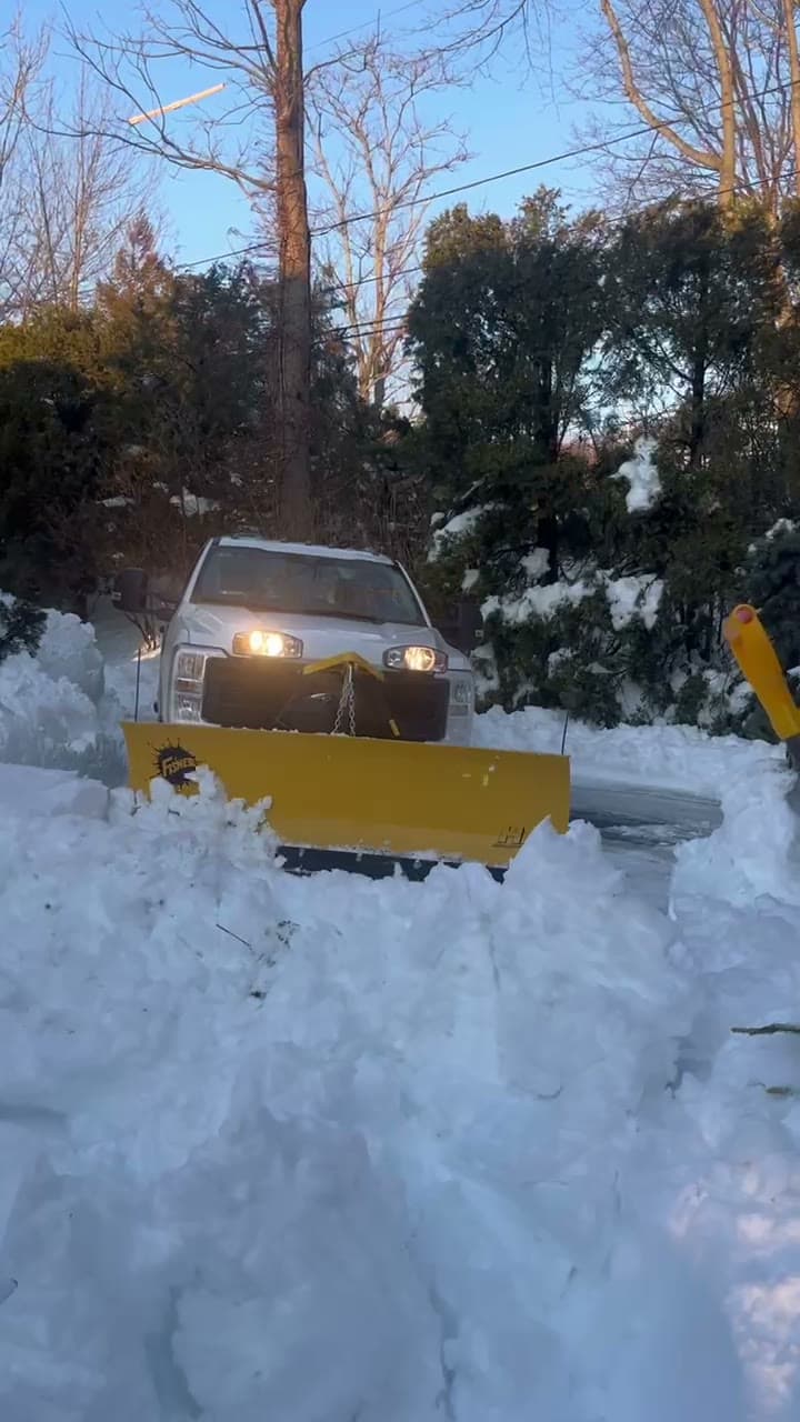 A LawnCheck truck plowing a snow-covered East Bay driveway at golden hour