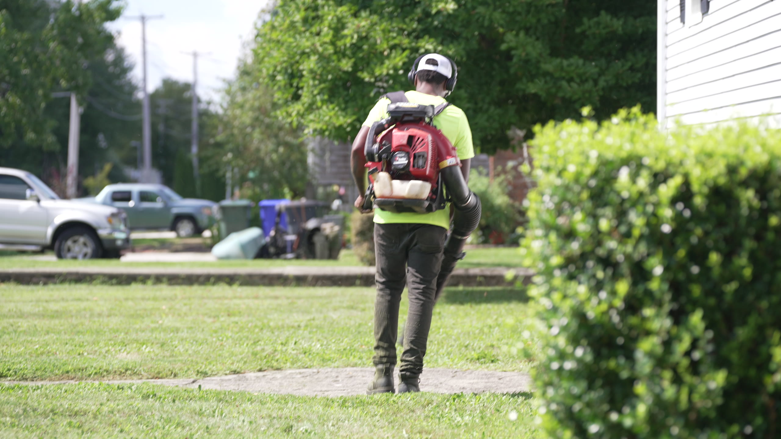 A crew member with a backpack blower clearing a lawn